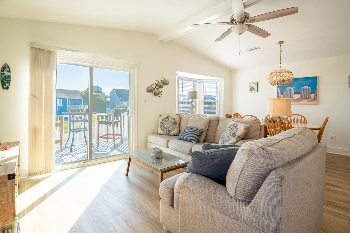 An inviting living room with a comfortable sofa and coffee table, bathed in natural light from a large window that offers a scenic view outside. The atmosphere is relaxed, hinting at peaceful moments spent enjoying the sunset or observing wildlife from indoors.
