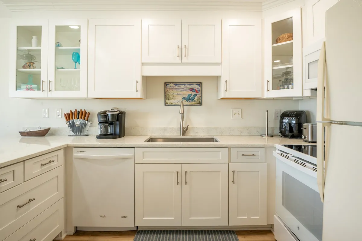 A stylish kitchen scene with white cabinetry, stainless steel appliances, a spacious countertop, and a decorative art piece. The setting is ideal for cooking, baking, and sharing stories while preparing meals together.